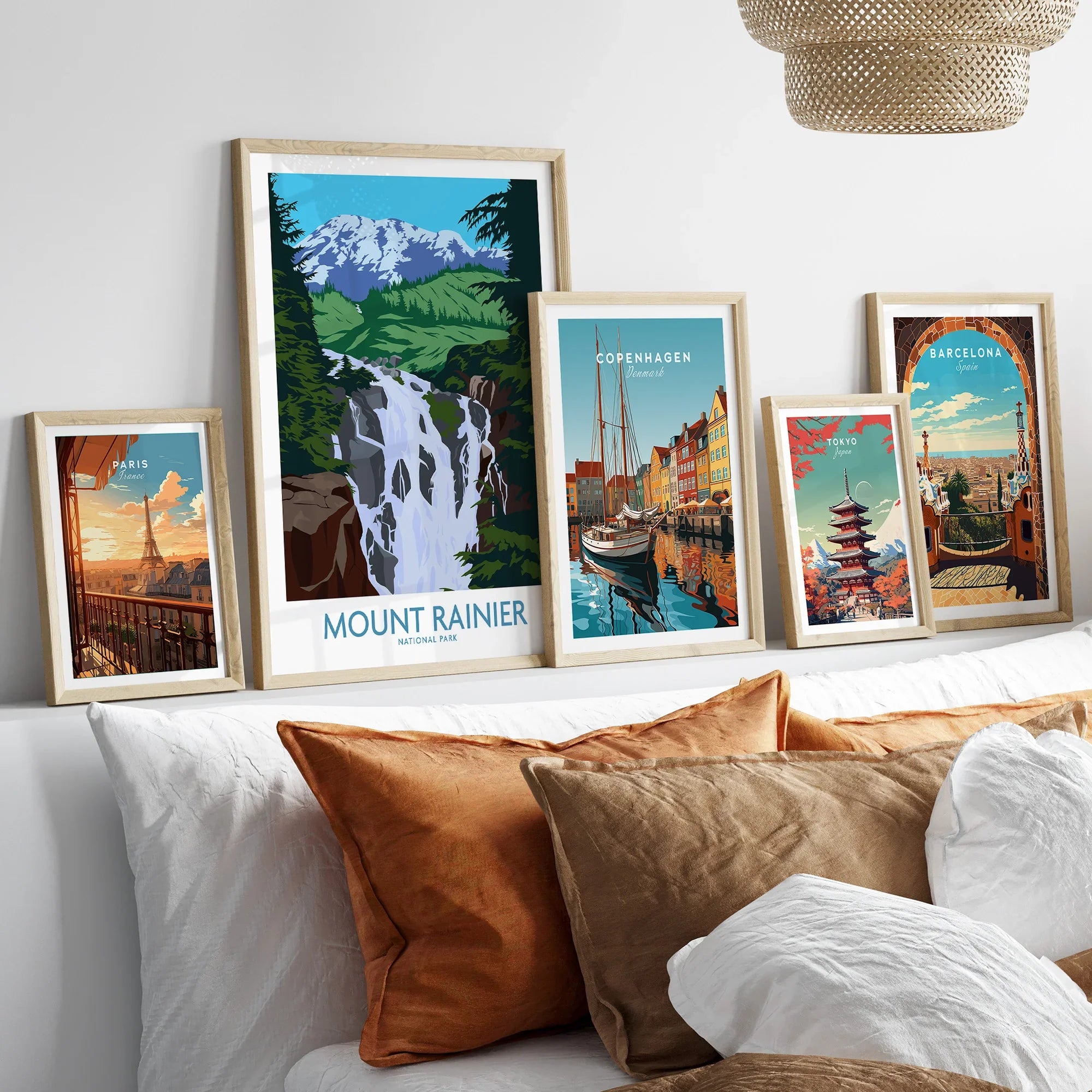 Set of five framed travel art prints above bed, featuring Paris, Mount Rainier, Copenhagen, Tokyo, Barcelona.