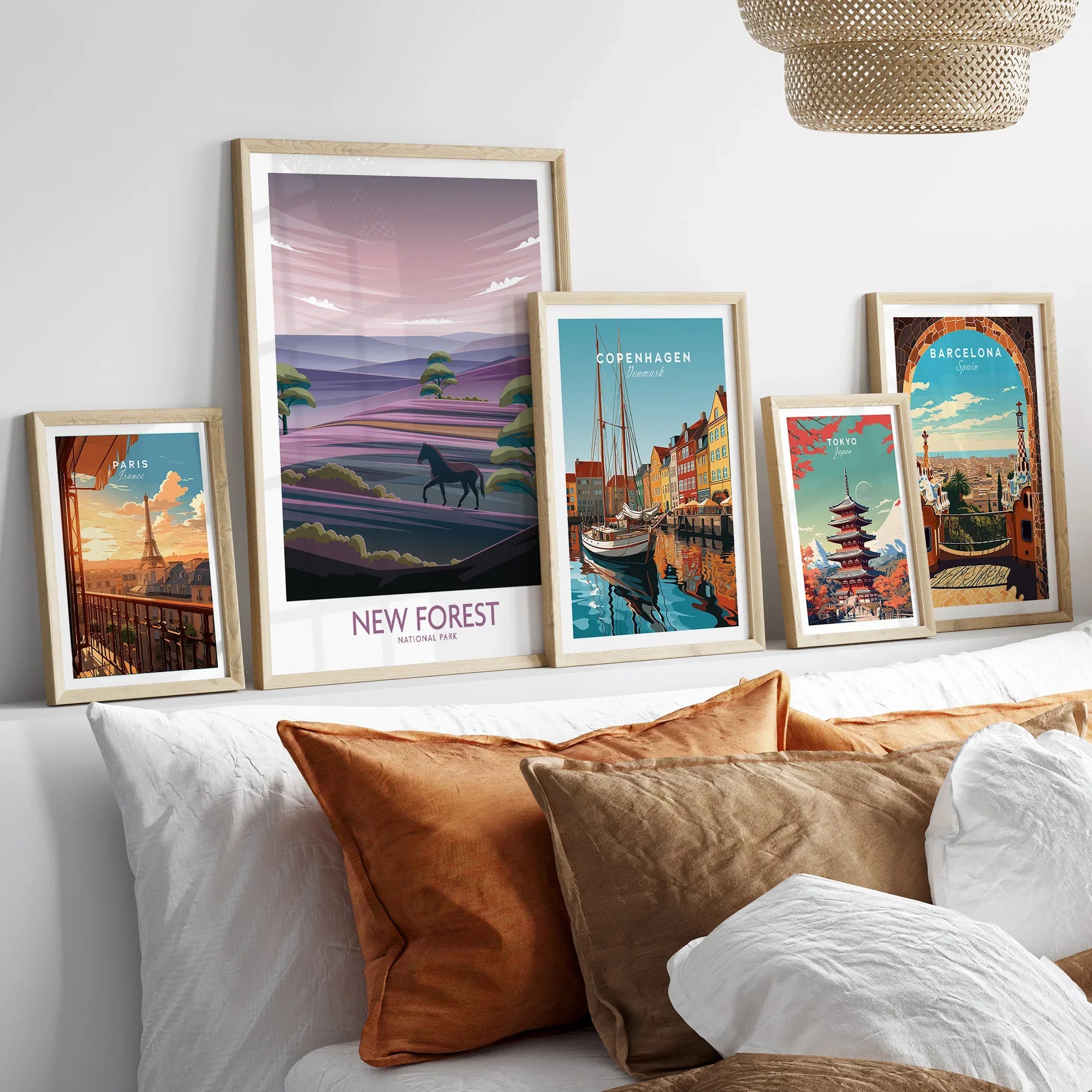 Five framed travel art prints of Paris, New Forest, Copenhagen, Tokyo, and Barcelona above bed