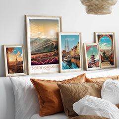 Framed travel posters of Paris, North York Moors, Copenhagen, Tokyo, and Barcelona above a bed.