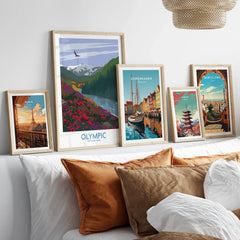 Framed travel posters of Paris, Olympic National Park, Copenhagen, Tokyo, and Barcelona above bed