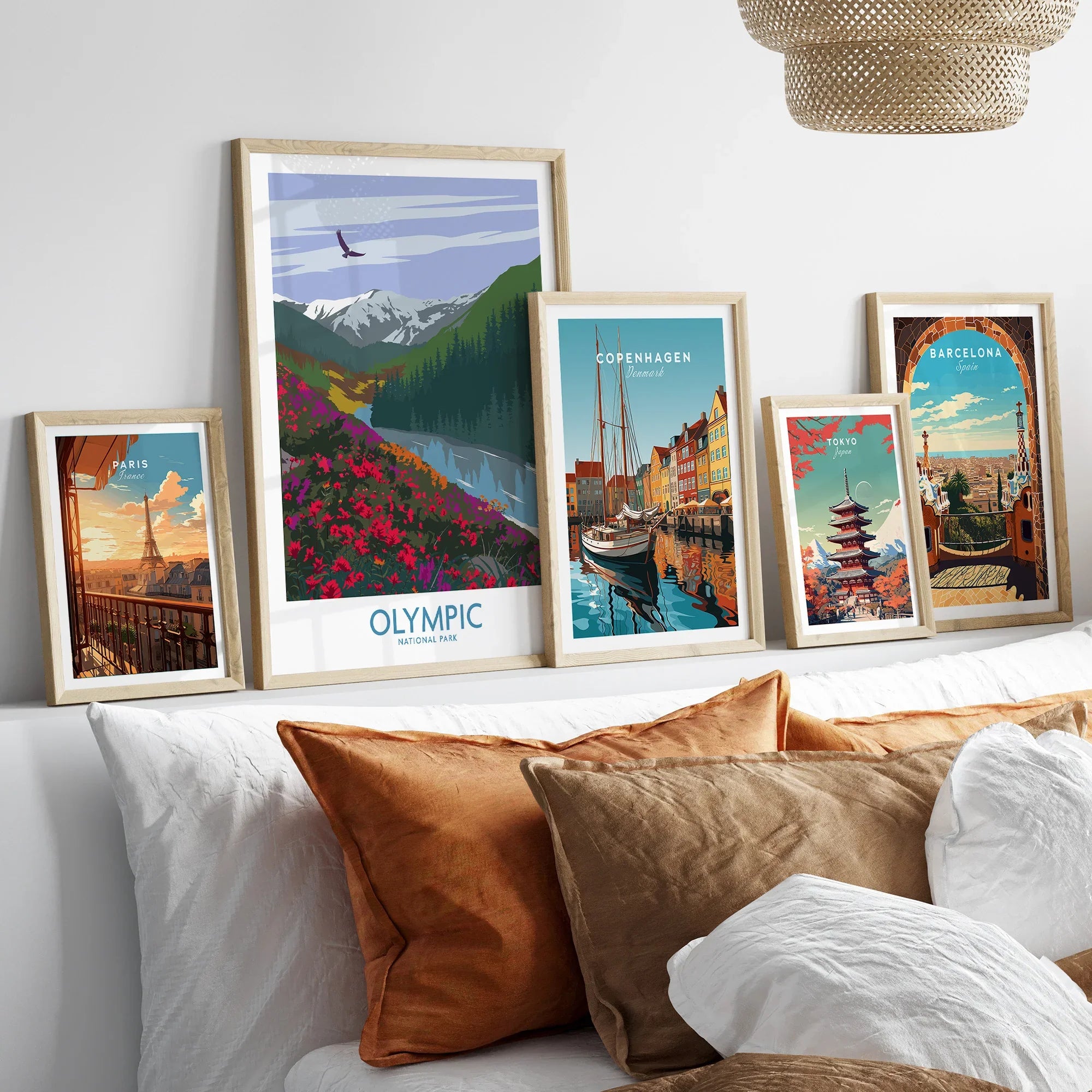 Framed travel posters of Paris, Olympic National Park, Copenhagen, Tokyo, and Barcelona above bed