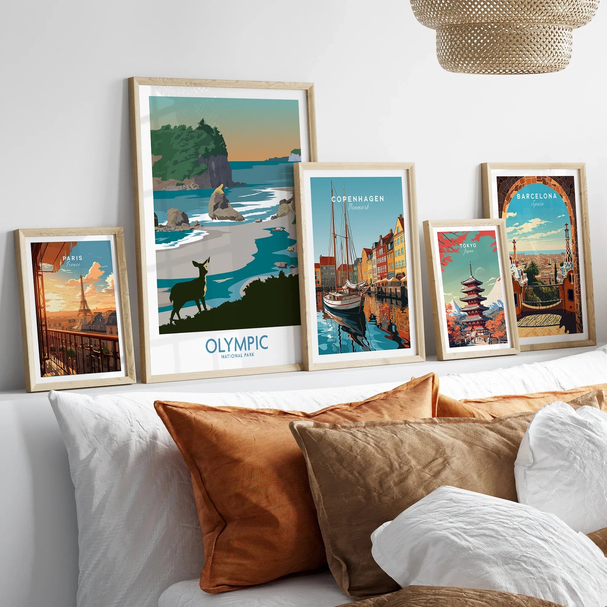 Set of five framed travel art prints above bed, featuring Paris, Olympic National Park, Copenhagen, Tokyo, and Barcelona.