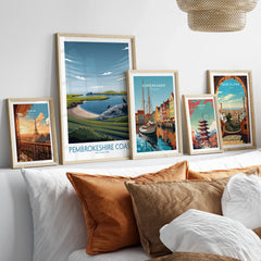 Framed travel posters of Paris, Pembrokeshire Coast, Copenhagen, Tokyo, and Barcelona above a bed.