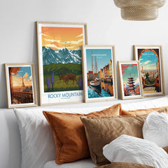 Set of five framed travel posters above bed, featuring Paris, Rocky Mountain, Copenhagen, Tokyo, and Barcelona art prints.