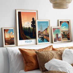 Set of five framed travel and city wall art prints above a bed with neutral pillows
