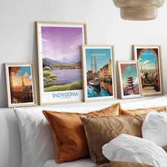 Five framed travel art prints of famous cities and landscapes above a modern bed