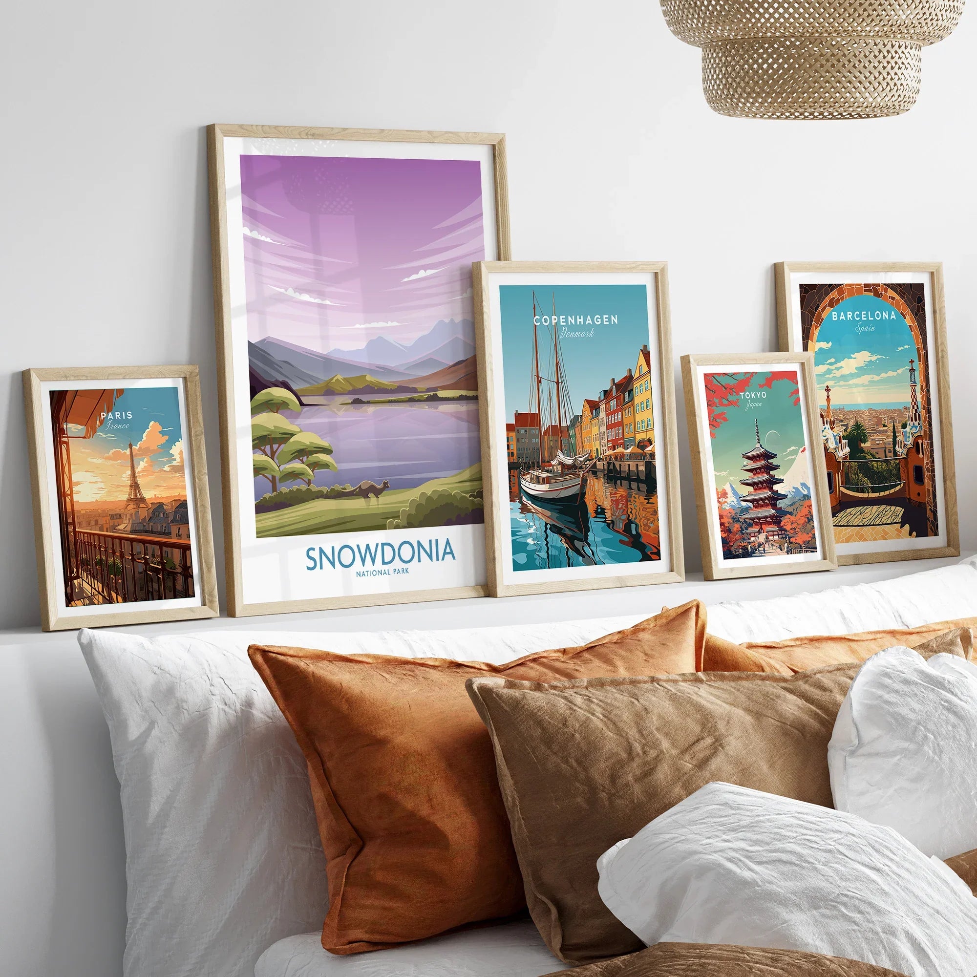 Five framed travel art prints of famous cities and landscapes above a modern bed