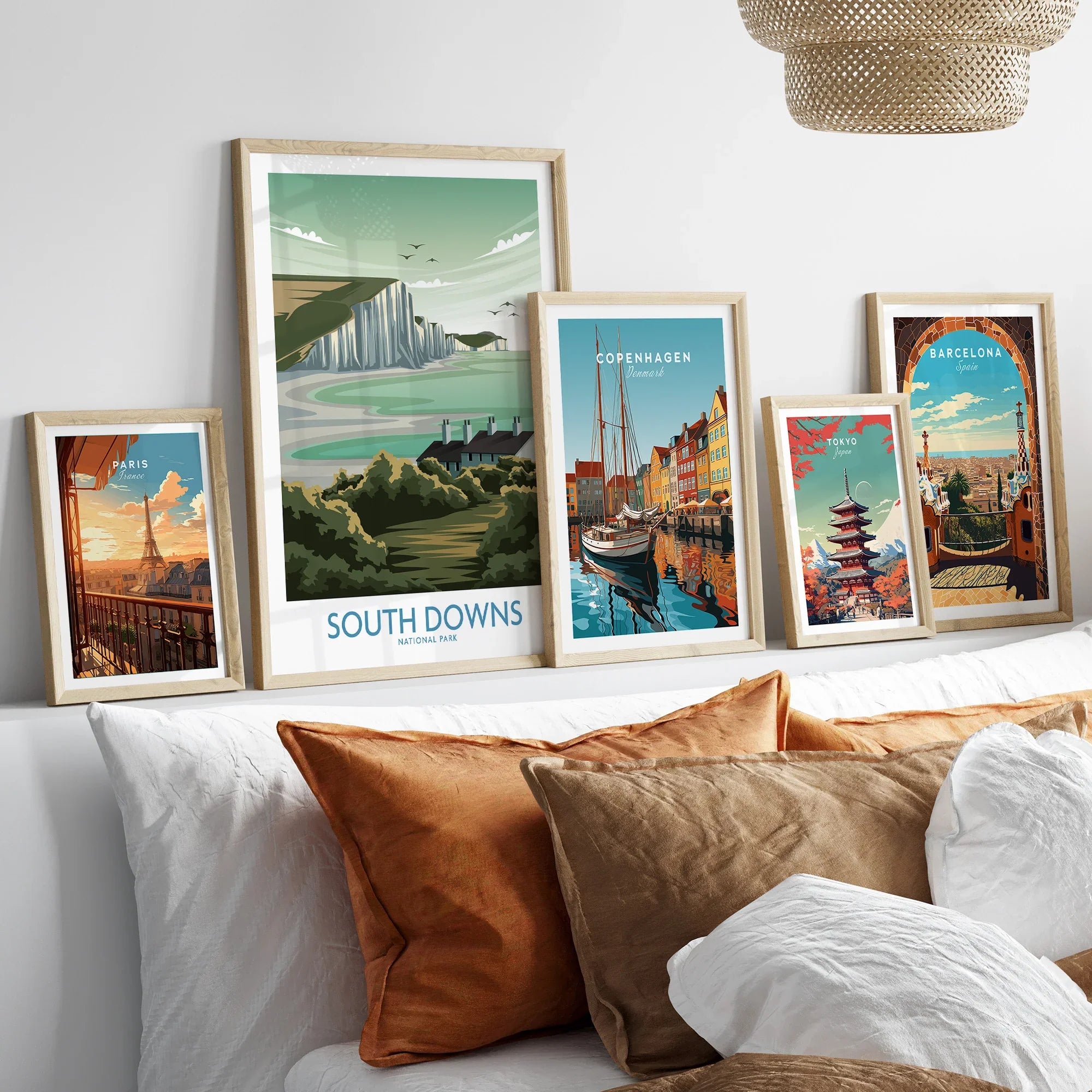 Set of five framed travel art prints above bed, featuring Paris, South Downs, Copenhagen, Tokyo, Barcelona.
