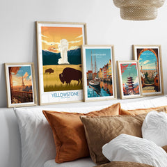 Framed travel art prints of Yellowstone, Paris, Copenhagen, Tokyo, and Barcelona above a bed