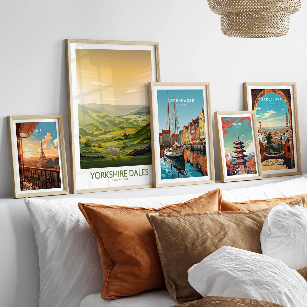 Framed travel art prints of Paris, Yorkshire Dales, Copenhagen, Tokyo, and Barcelona above a bed