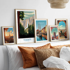 Framed travel art prints of Yosemite, Paris, Copenhagen, Tokyo, and Barcelona above a bed.