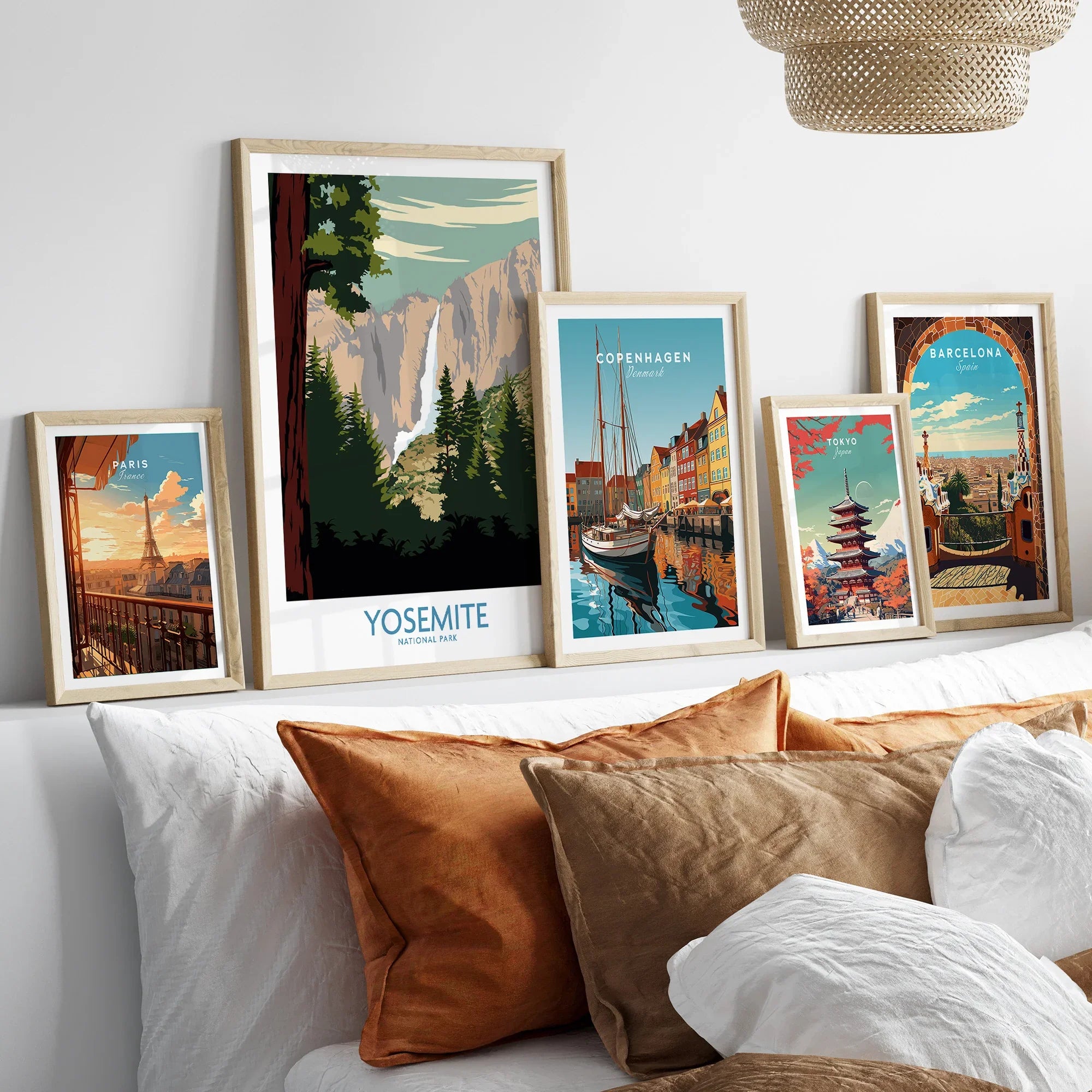 Framed travel art prints of Yosemite, Paris, Copenhagen, Tokyo, and Barcelona above a bed.