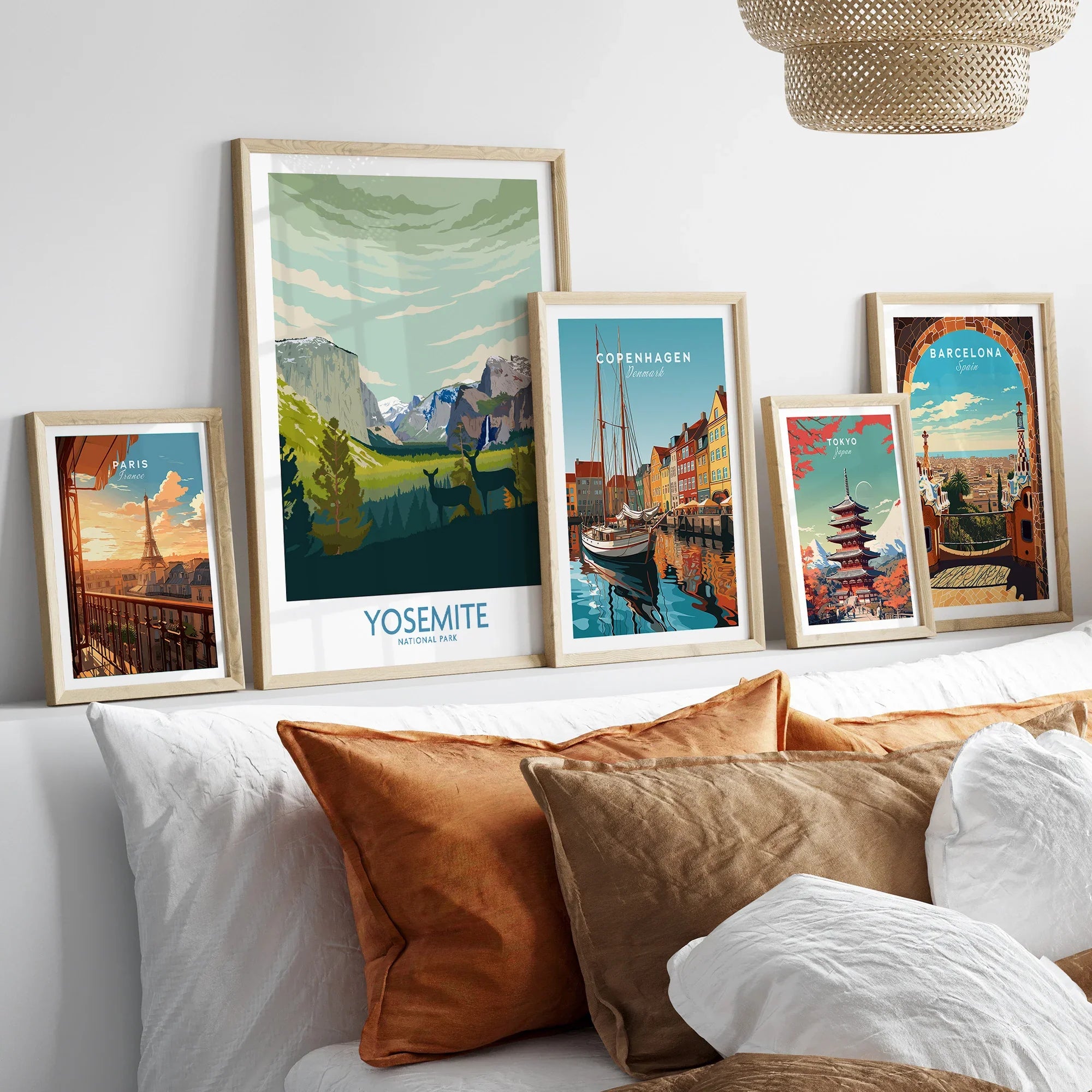 Five framed travel posters of Paris, Yosemite, Copenhagen, Tokyo, and Barcelona above a bed.