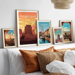 Set of five framed travel art prints above bed, featuring Monument Valley, Paris, Copenhagen, Tokyo, and Barcelona.