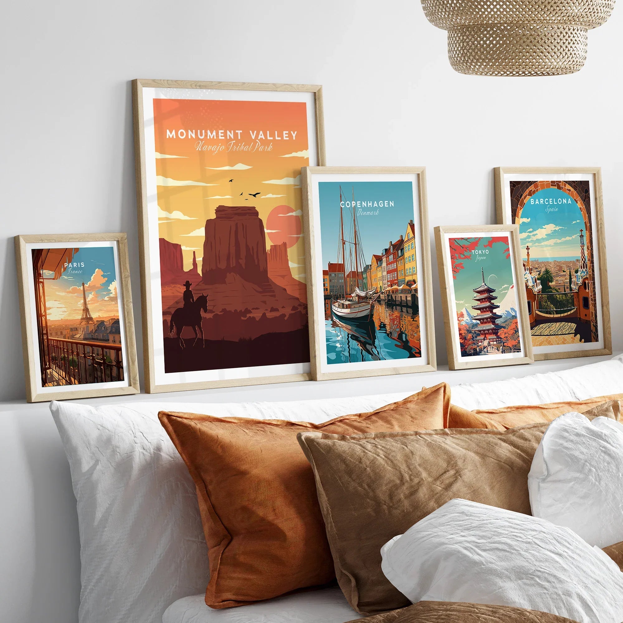 Set of five framed travel art prints above bed, featuring Monument Valley, Paris, Copenhagen, Tokyo, and Barcelona.
