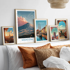 Five framed travel art prints of Paris, Mount Etna, Copenhagen, Tokyo, and Barcelona above bed