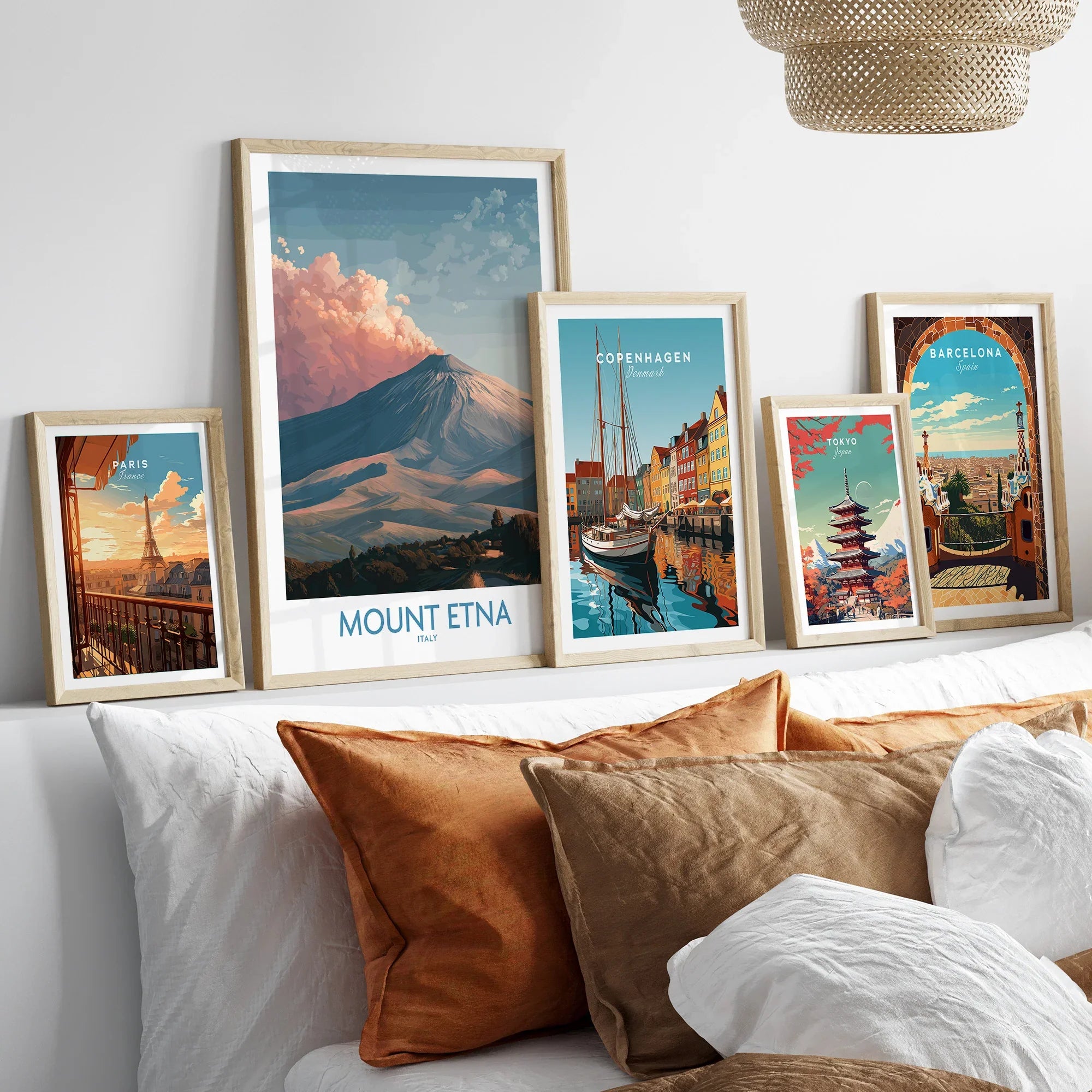 Five framed travel art prints of Paris, Mount Etna, Copenhagen, Tokyo, and Barcelona above bed