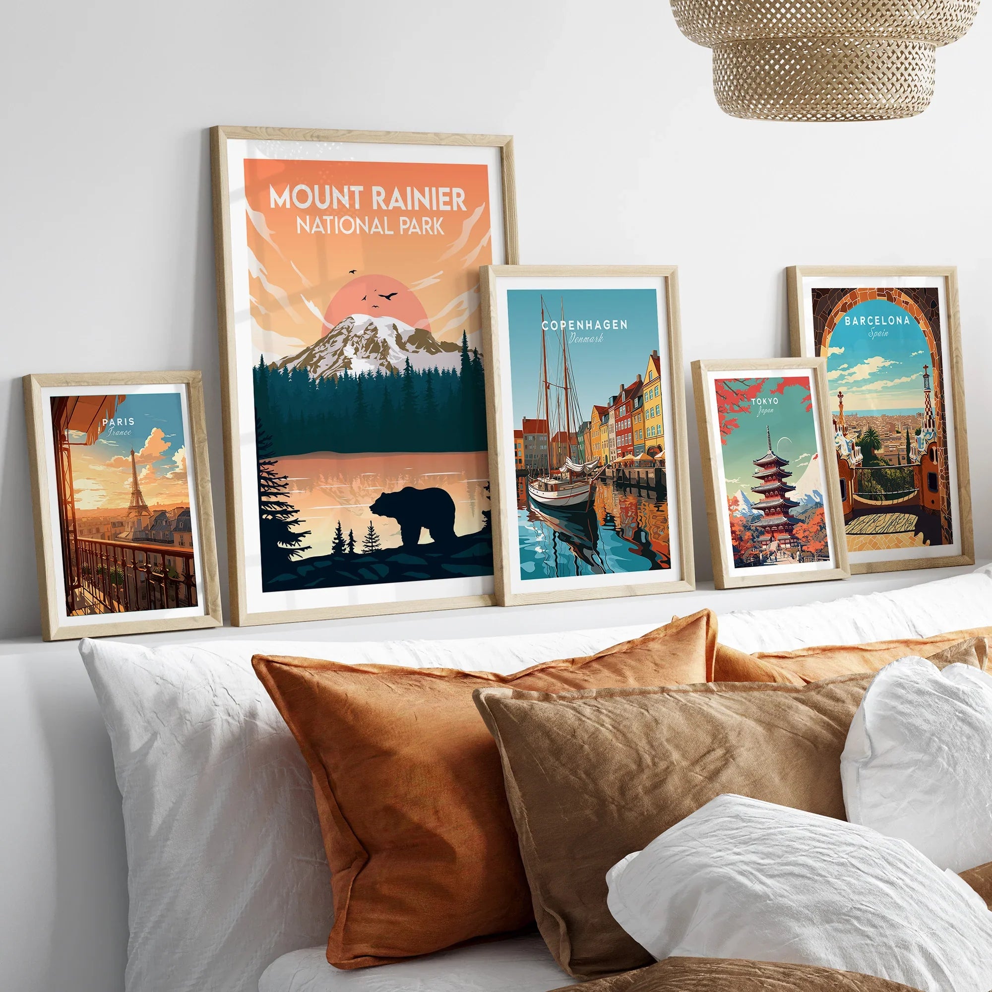 Framed travel posters of Mount Rainier, Paris, Copenhagen, Tokyo, and Barcelona above bed