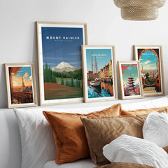 Five framed travel art prints featuring global landmarks above a modern bed with pillows.