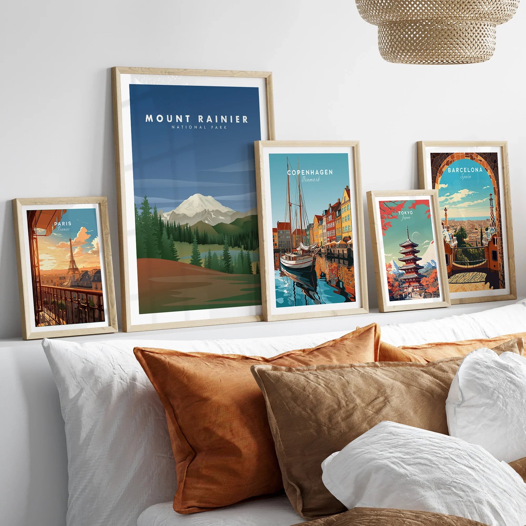 Five framed travel art prints featuring global landmarks above a modern bed with pillows.