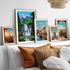 Framed travel art prints of Mount Rainier, Paris, Copenhagen, Tokyo, and Barcelona above bed