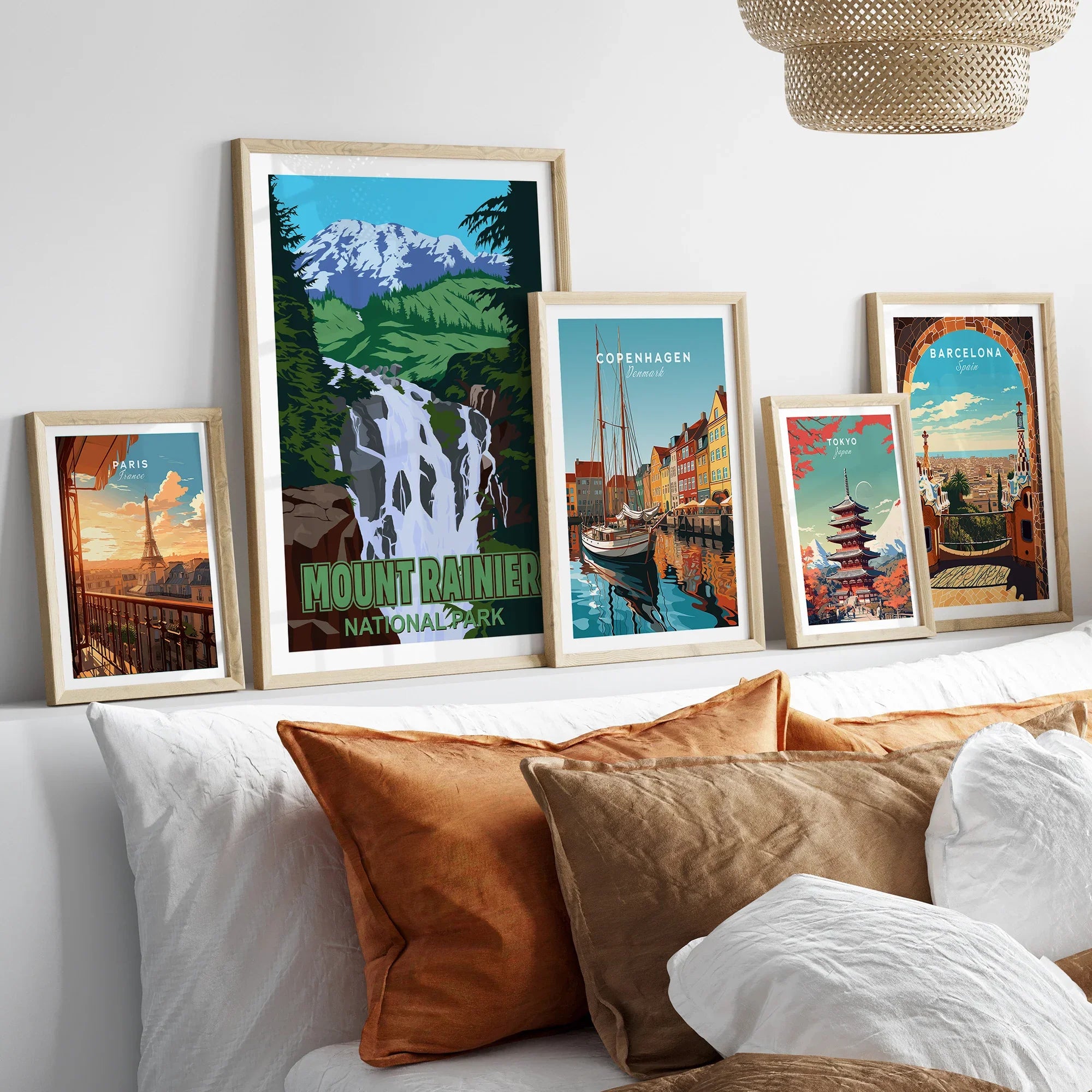 Framed travel art prints of Mount Rainier, Paris, Copenhagen, Tokyo, and Barcelona above bed