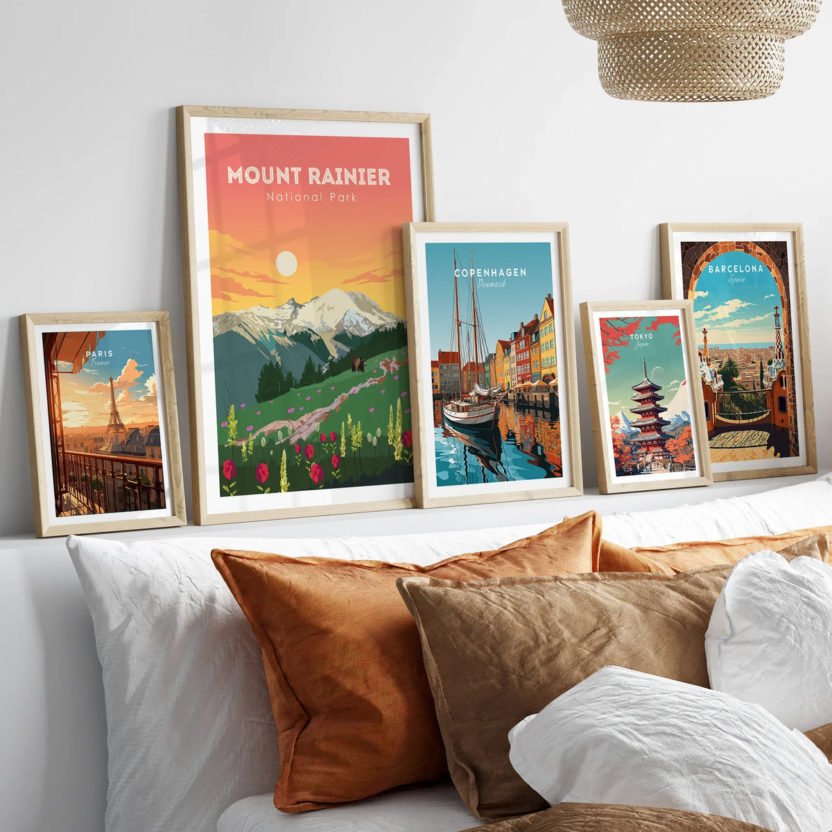 Framed travel posters of Mount Rainier, Paris, Copenhagen, Tokyo, and Barcelona above a bed.