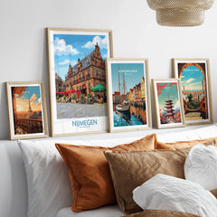 Set of five framed travel posters above bed, featuring Paris, Nijmegen, Copenhagen, Tokyo, and Barcelona skyline art prints in natural wood frames.