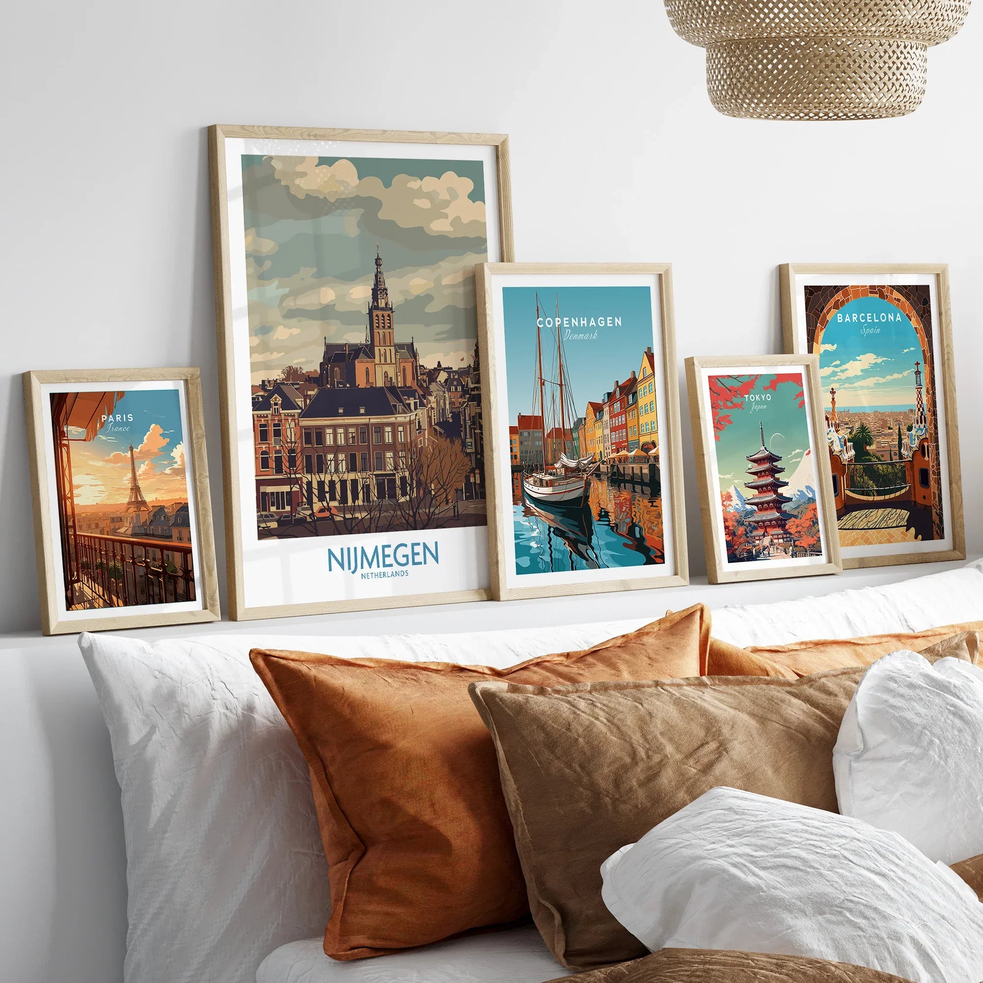Set of five framed travel posters featuring city skylines above a bed with natural wood frames.