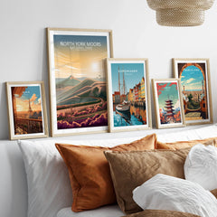 Set of five framed travel art prints above bed featuring Paris, North York Moors, Copenhagen, Tokyo, Barcelona.