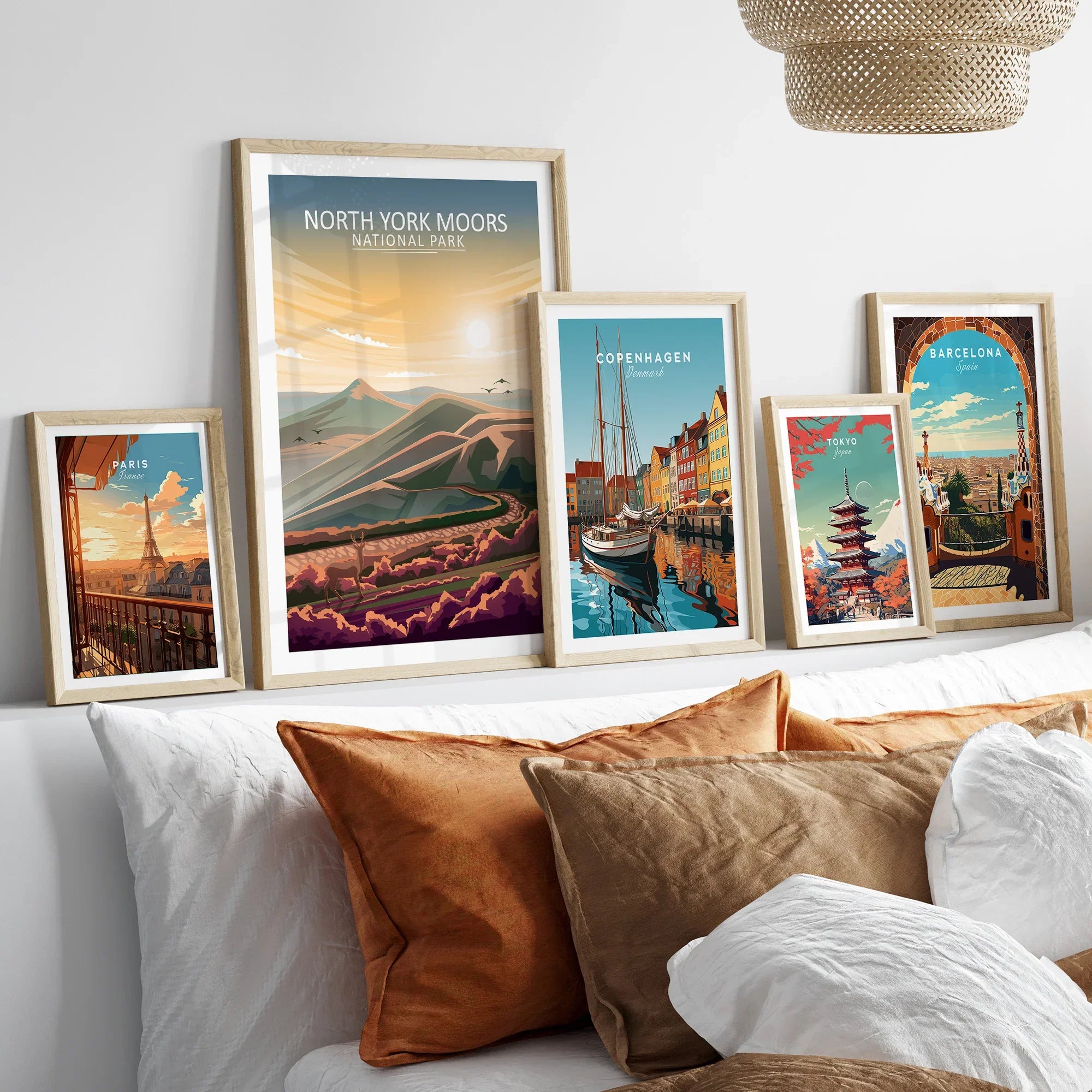 Set of five framed travel art prints above bed featuring Paris, North York Moors, Copenhagen, Tokyo, Barcelona.