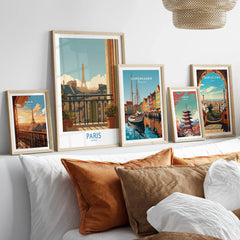 Set of five framed travel posters featuring Paris, Copenhagen, Tokyo, and Barcelona above bed
