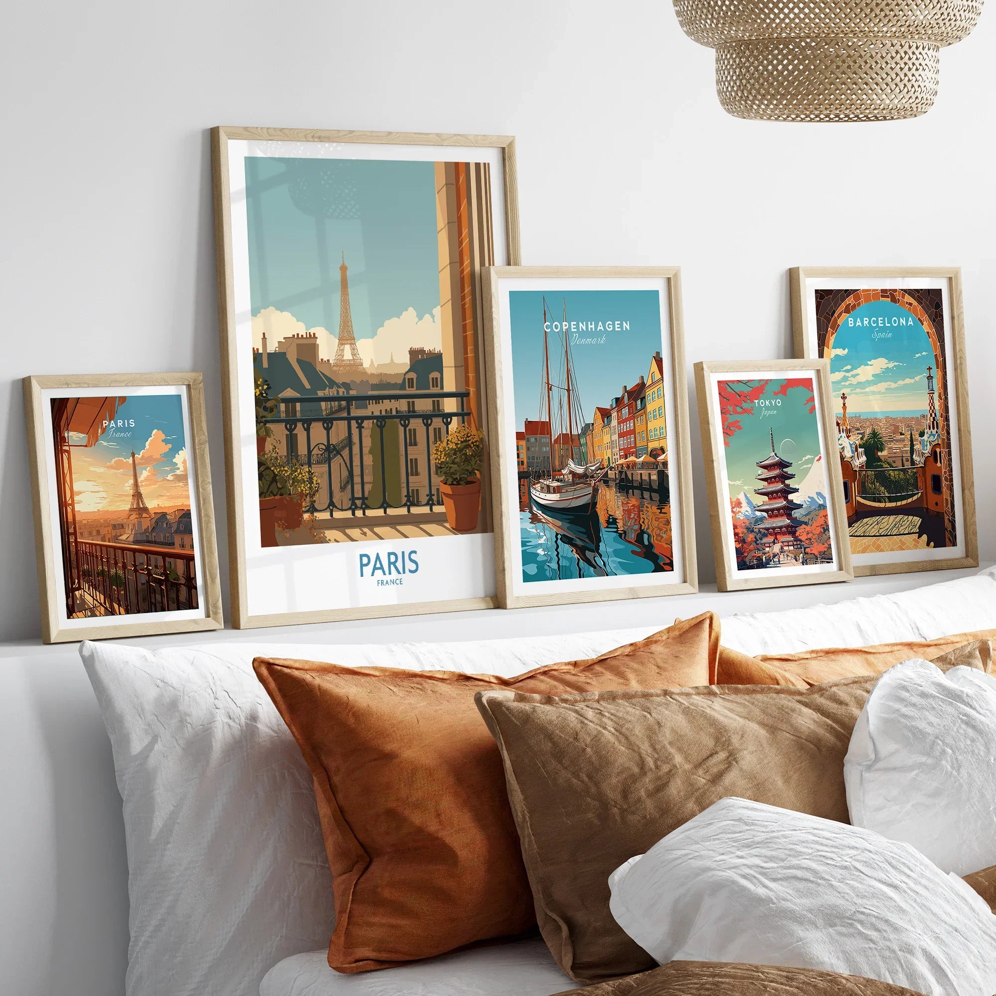 Set of five framed travel posters featuring Paris, Copenhagen, Tokyo, and Barcelona above bed