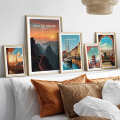 Framed travel posters of Paris, Madeira, Copenhagen, Tokyo, and Barcelona above a bed.