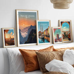 Set of five framed travel posters above bed, featuring Paris, Pico do Arieiro, Copenhagen, Tokyo, Barcelona.