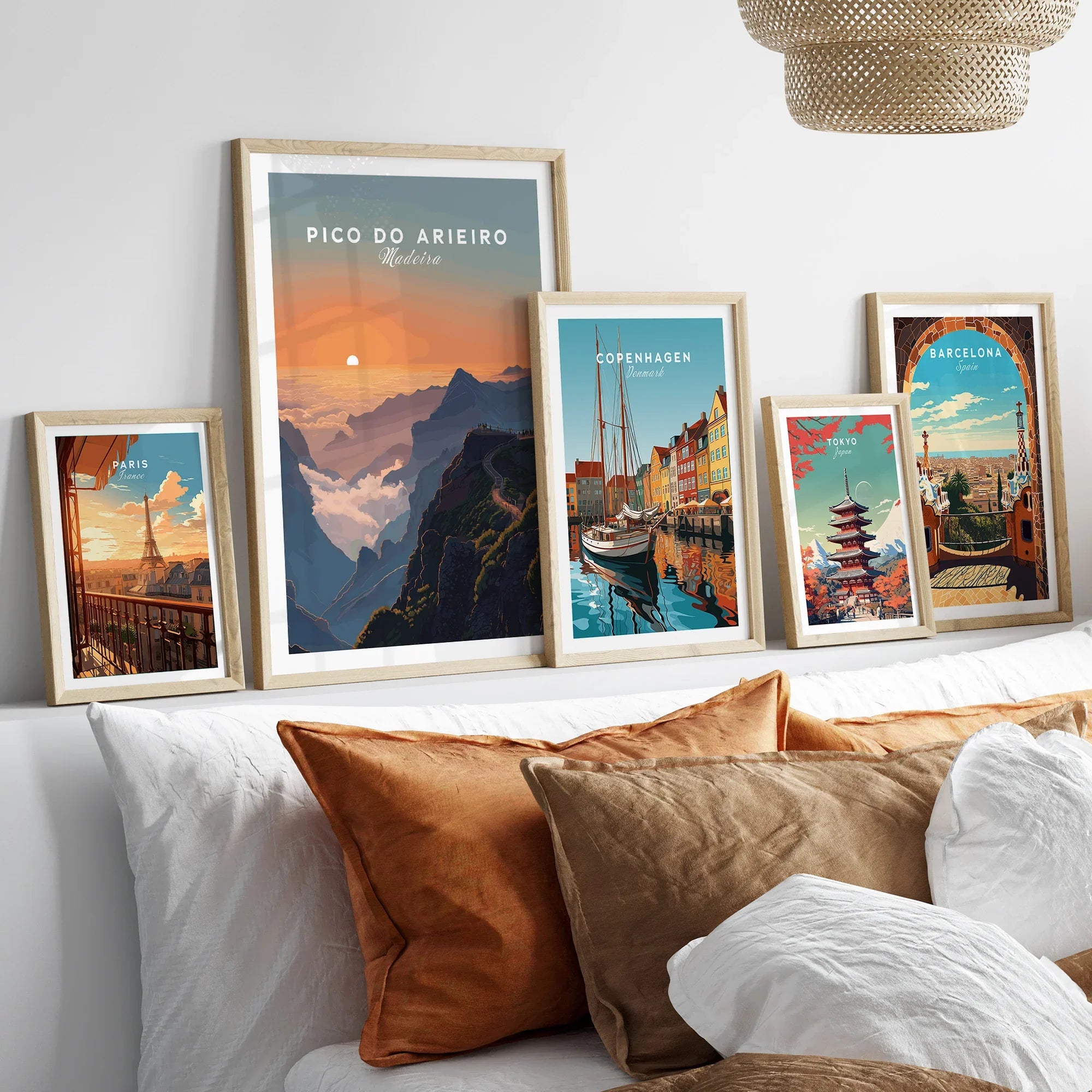 Set of five framed travel posters above bed, featuring Paris, Pico do Arieiro, Copenhagen, Tokyo, Barcelona.