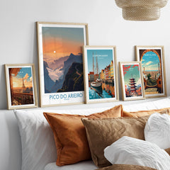 Set of five framed travel posters above bed, featuring Paris, Pico do Arieiro, Copenhagen, Tokyo, Barcelona.