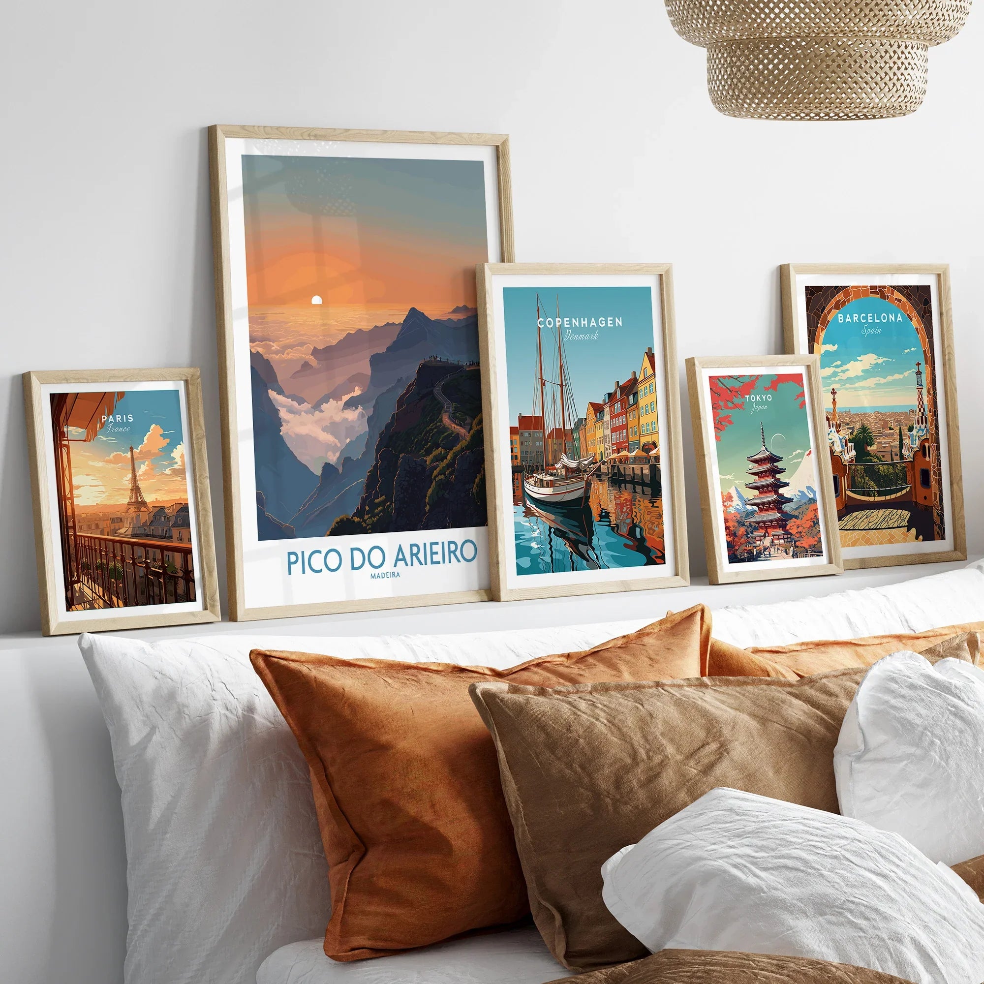 Set of five framed travel posters above bed, featuring Paris, Pico do Arieiro, Copenhagen, Tokyo, Barcelona.