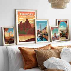 Framed travel posters of Pinnacles National Park, Paris, Copenhagen, Tokyo, and Barcelona above bed