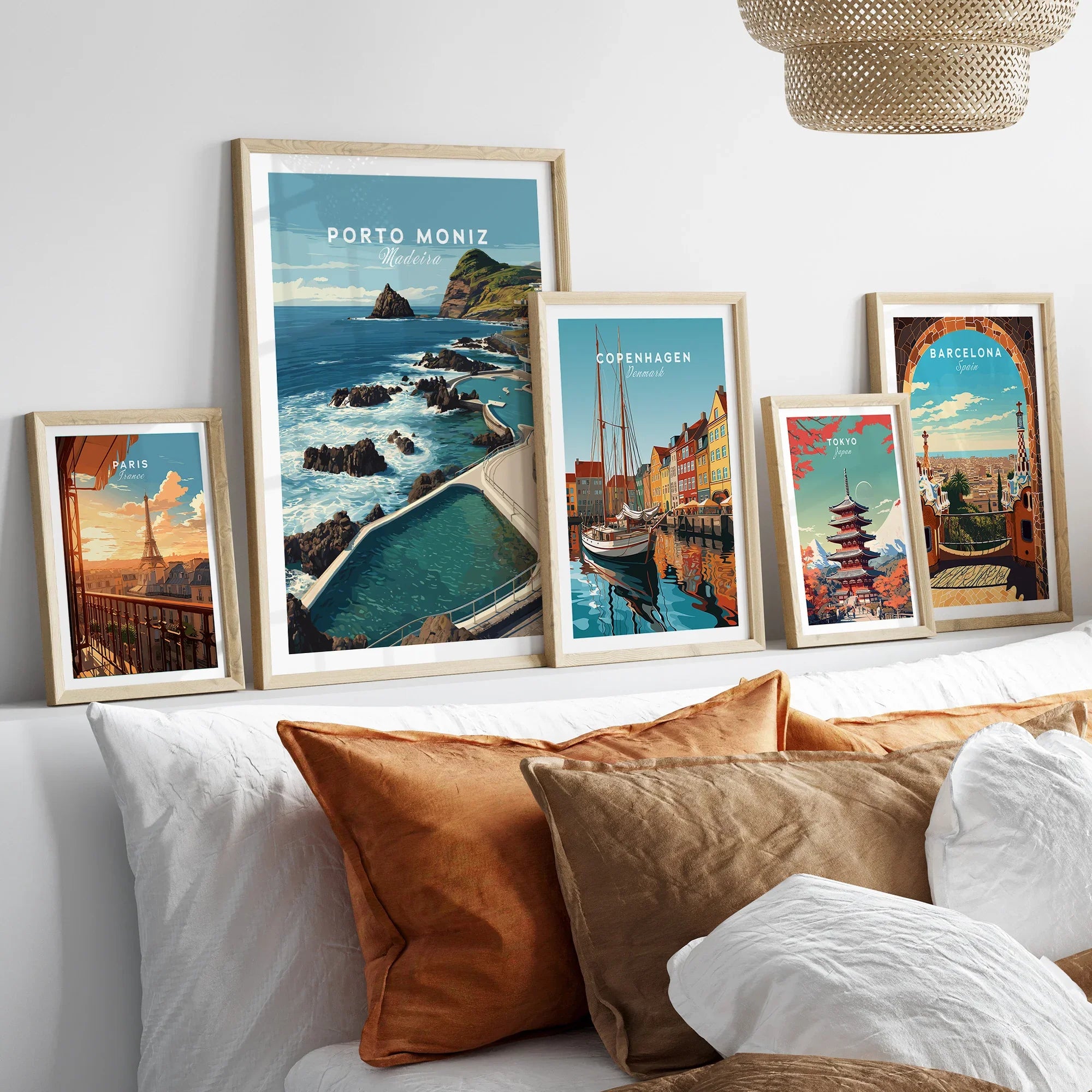 Set of five framed travel posters above bed featuring Paris, Porto Moniz, Copenhagen, Tokyo, Barcelona.