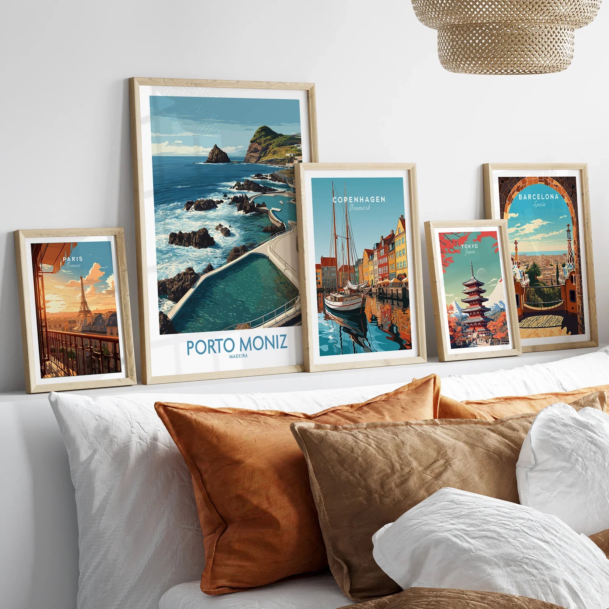 Framed travel art prints of Paris, Porto Moniz, Copenhagen, Tokyo, and Barcelona above bed