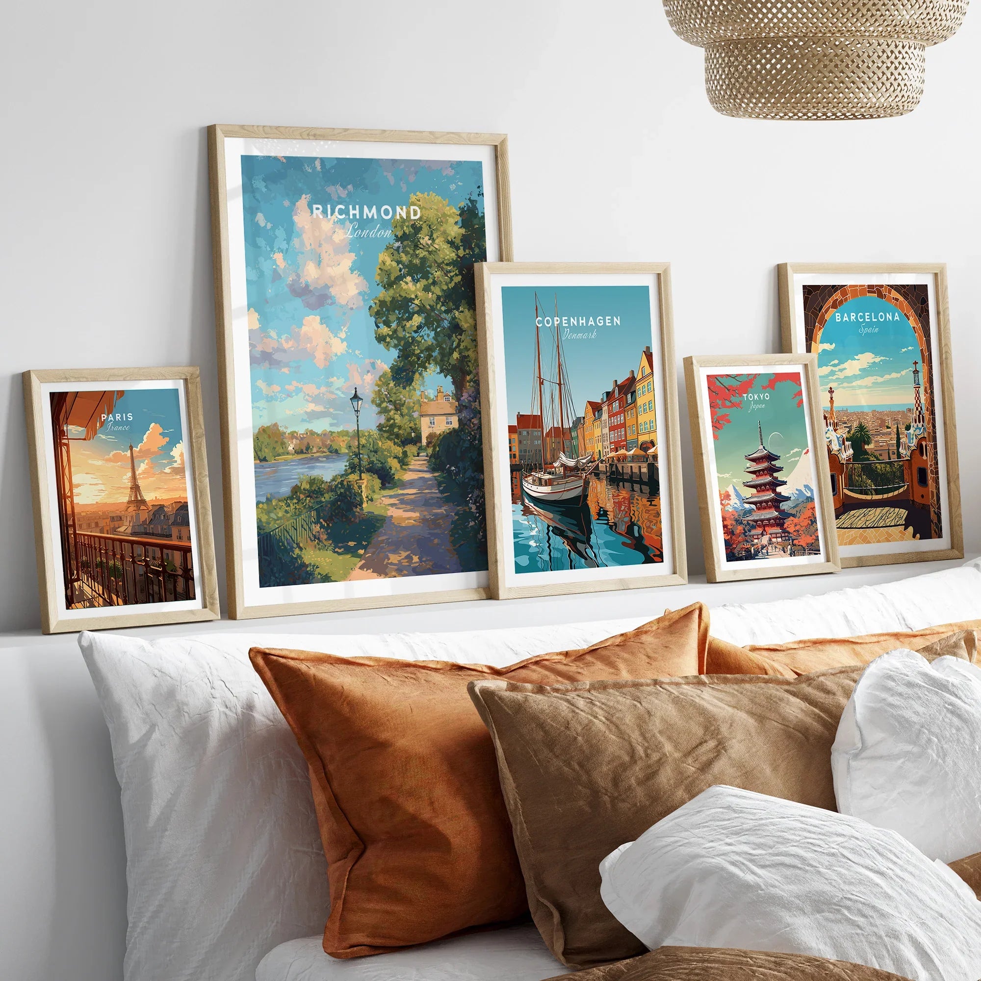 Set of five framed travel posters above a bed, featuring Paris, Richmond, Copenhagen, Tokyo, Barcelona landmarks.