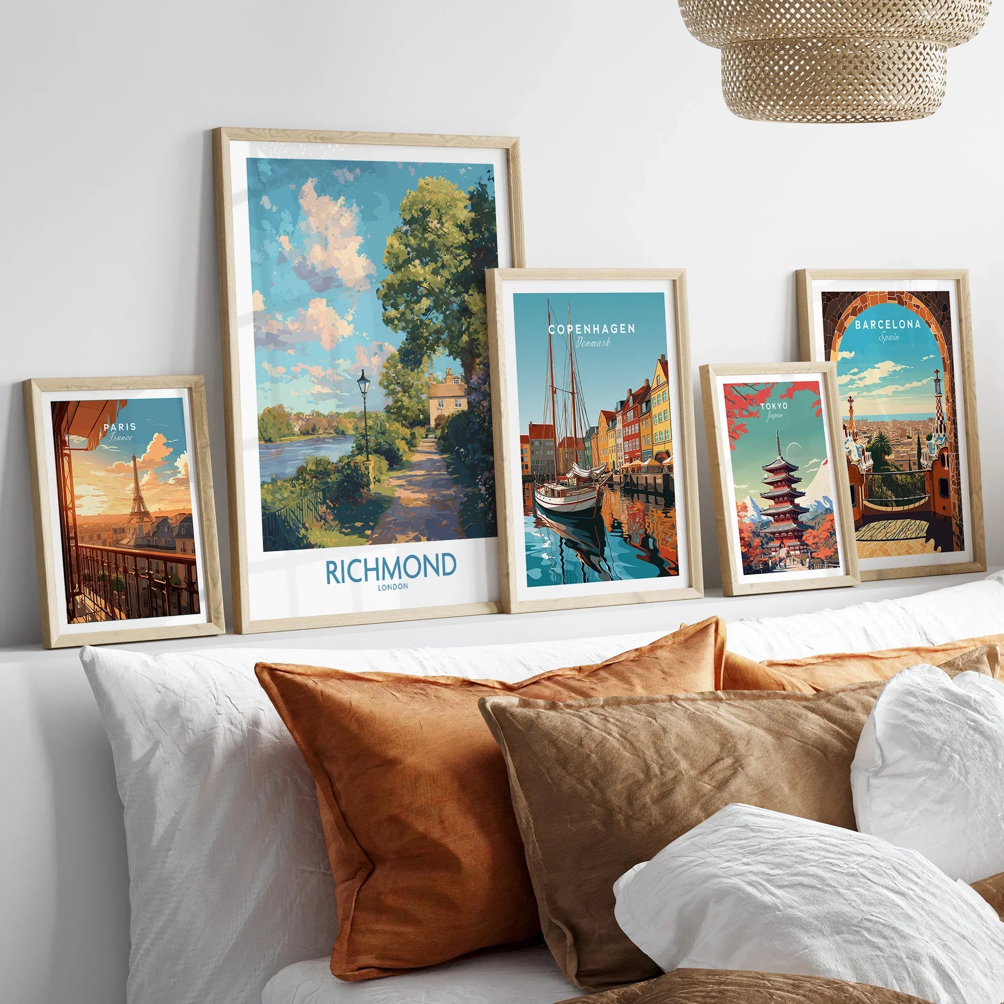 Travel city art prints in natural wood frames above bed with rustic pillows
