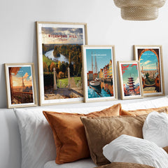 Set of five framed travel posters above bed, featuring Paris, London, Copenhagen, Tokyo, Barcelona.
