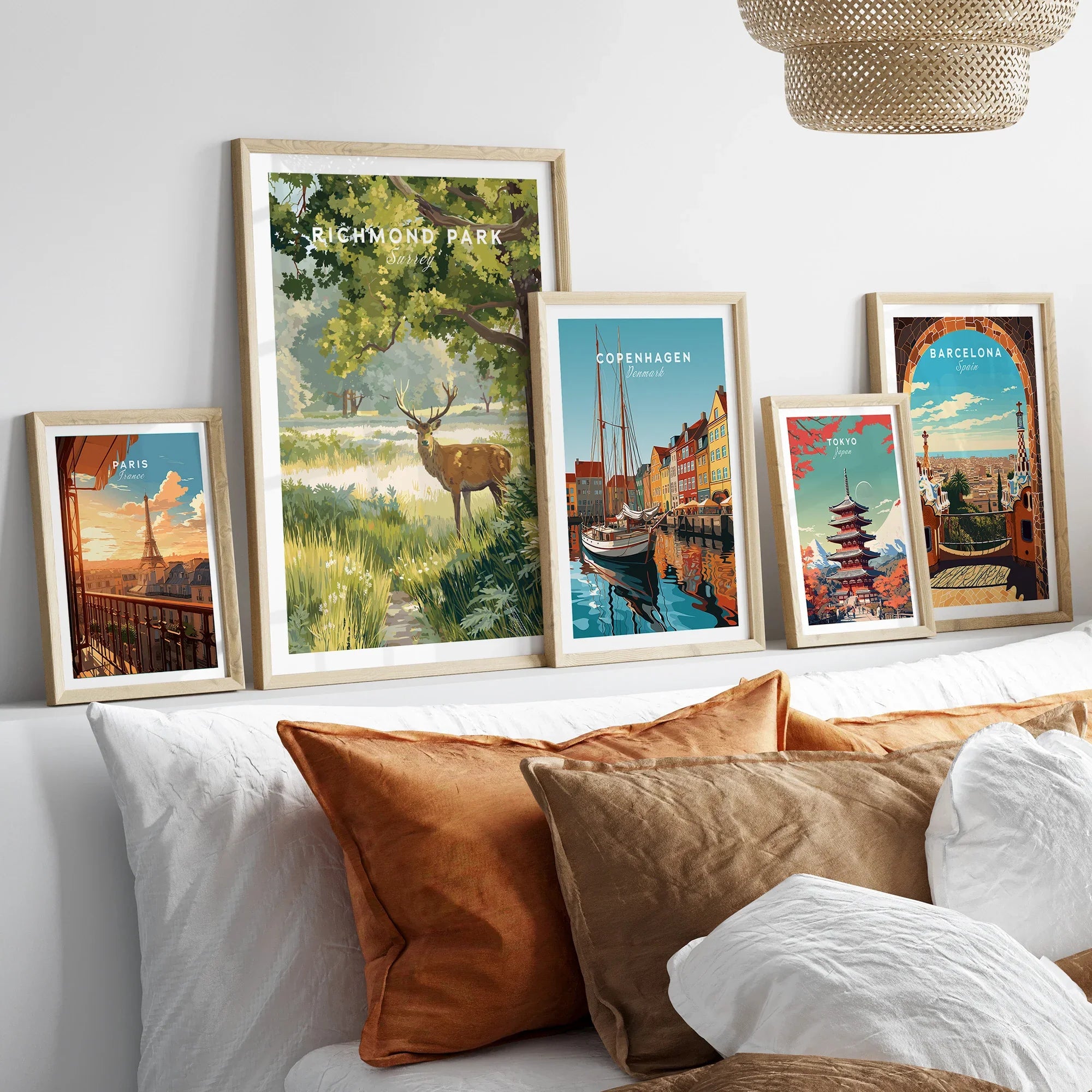 Framed travel art prints of Paris, Richmond Park, Copenhagen, Tokyo, and Barcelona above bed.