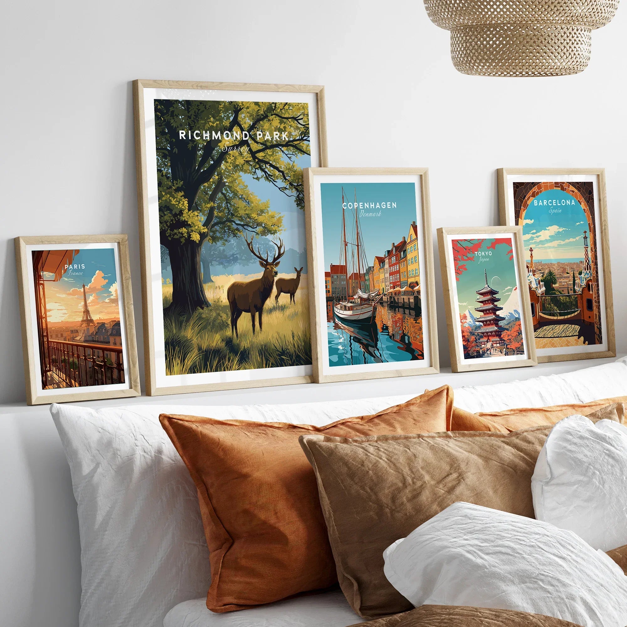 Set of five framed travel art prints above bed, featuring Paris, Richmond Park, Copenhagen, Tokyo, and Barcelona.