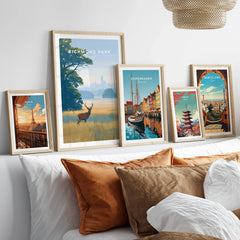 Travel art prints of Richmond Park, Paris, Copenhagen, Tokyo, Barcelona in natural wood frames above bed.