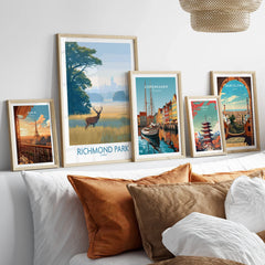 Set of five framed travel poster art prints above a bed with natural wood frames
