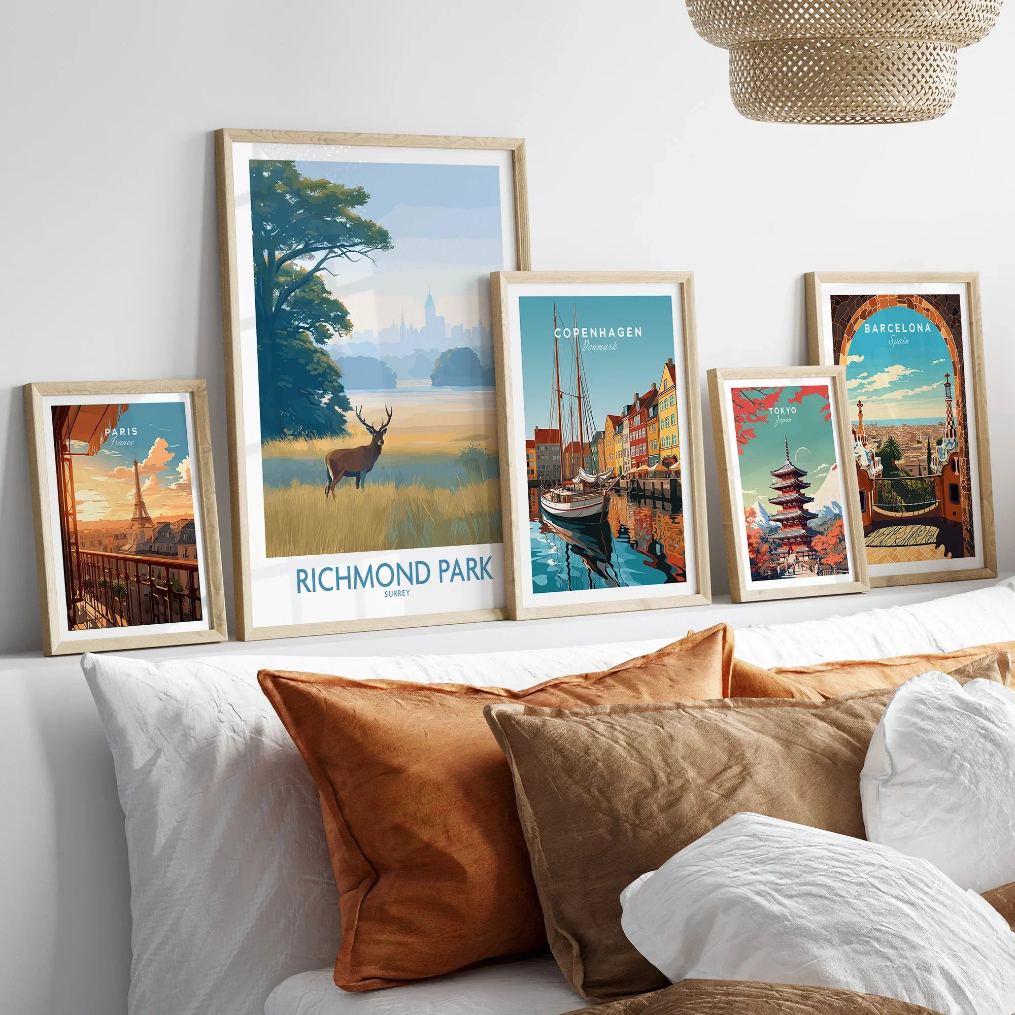 Set of five framed travel poster art prints above a bed with natural wood frames