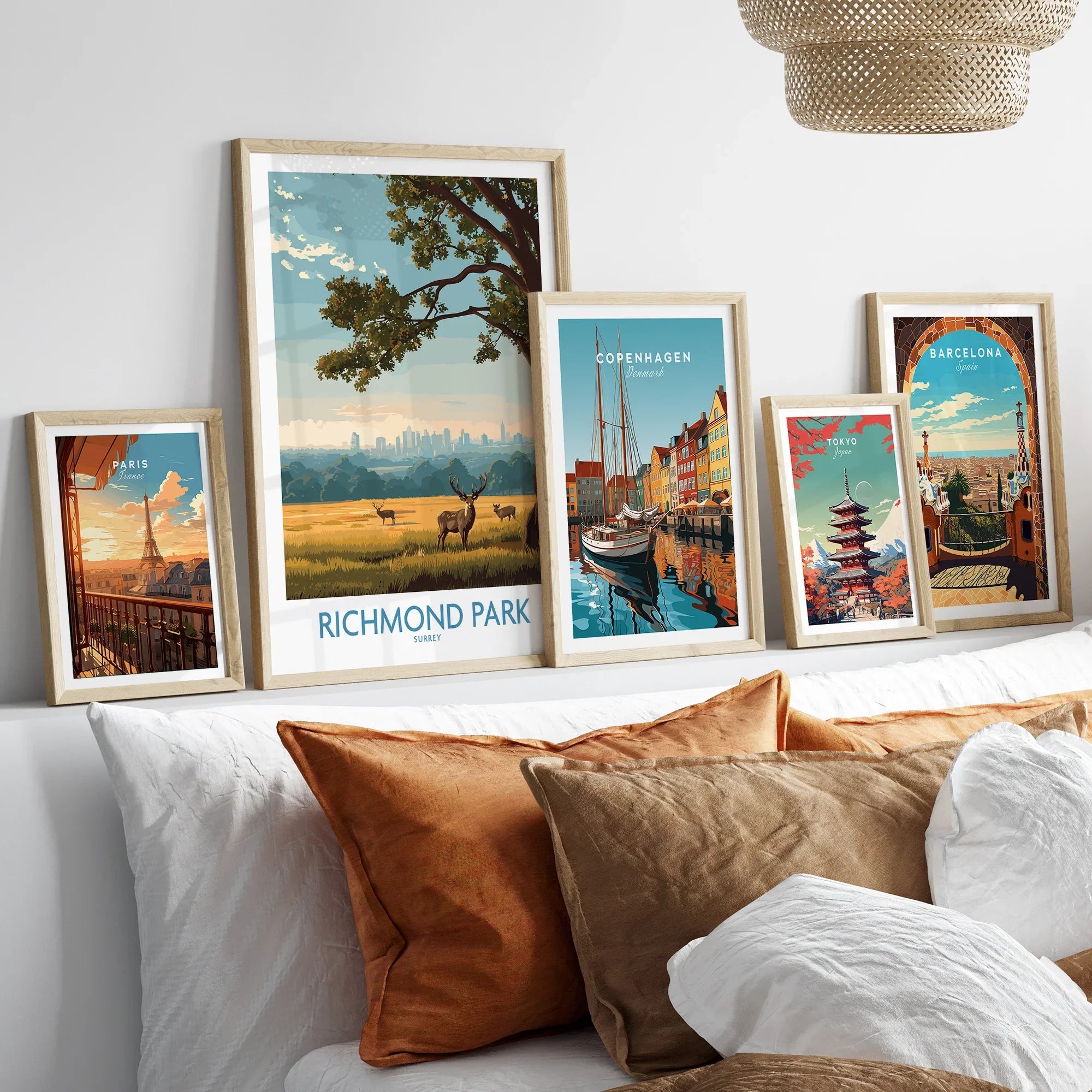 Five framed travel posters with city and nature scenes above a bed with neutral wood frames.